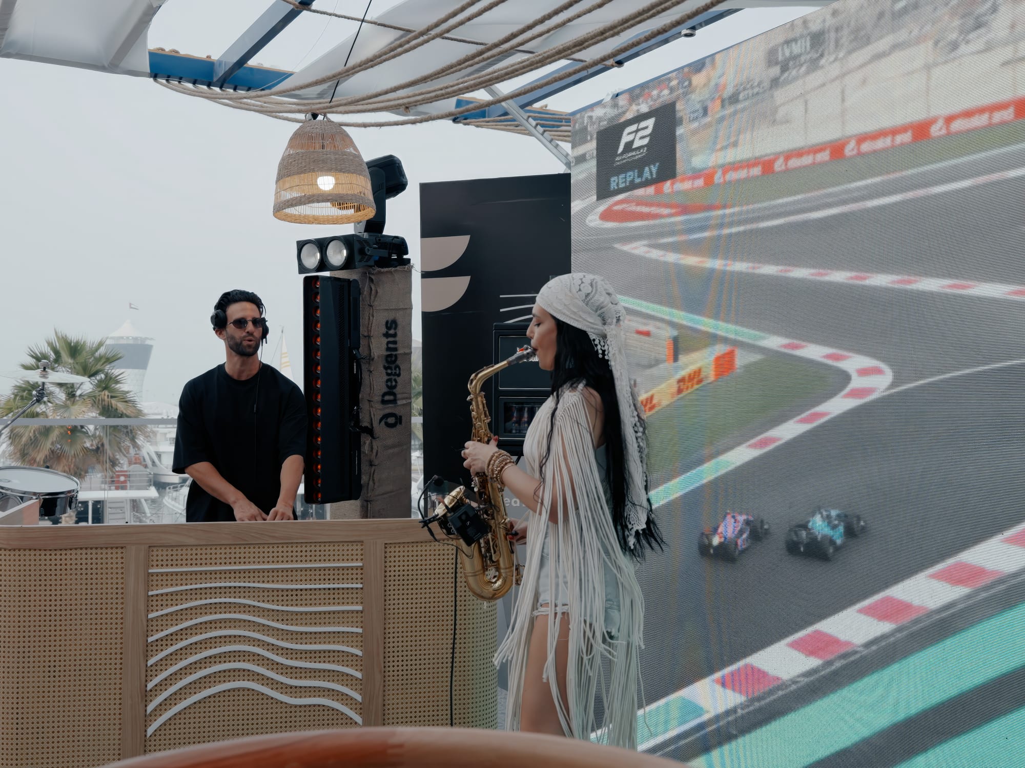 DJ and saxophonist with race replay on screen